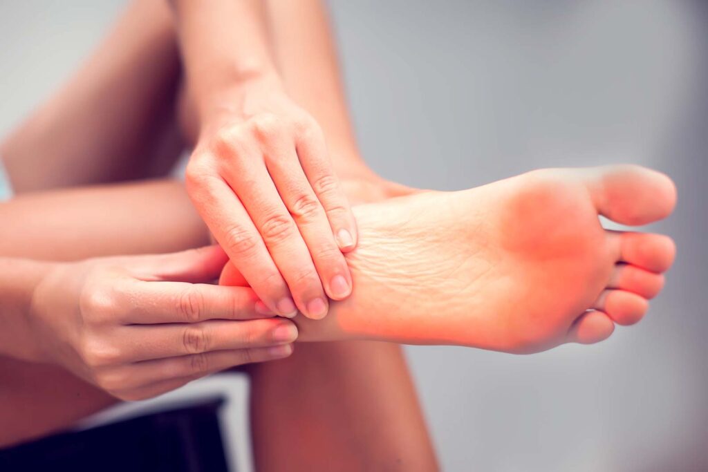 the bottom of a persons foot with both of their hands holding the heel area