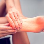 the bottom of a persons foot with both of their hands holding the heel area