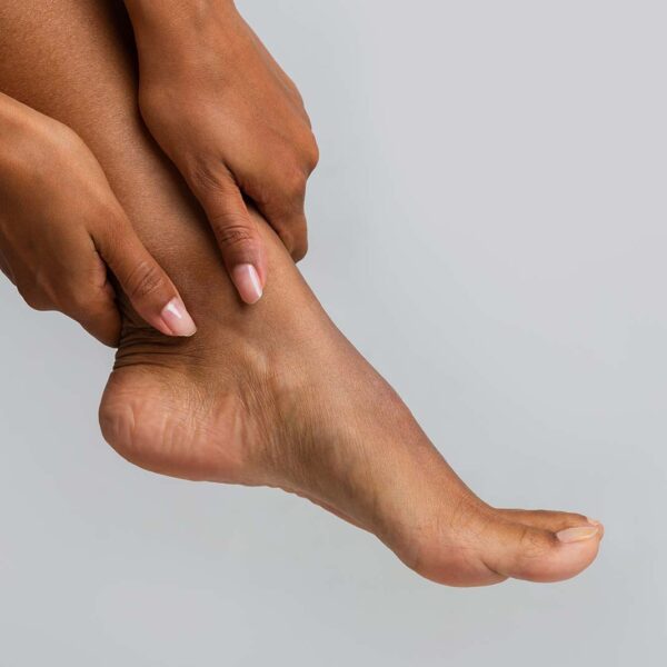 person holding their ankle area. Image shows foot and lower calf area and both hands