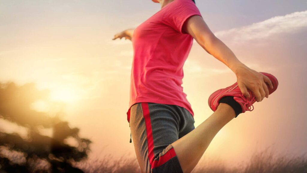 female jogger holding her foot up behind her buttocks to stretch