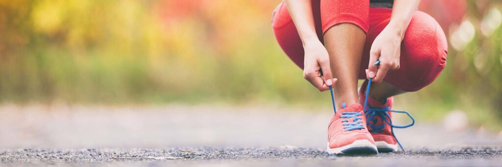 jogger in crop trousers kneeling down tying their laces
