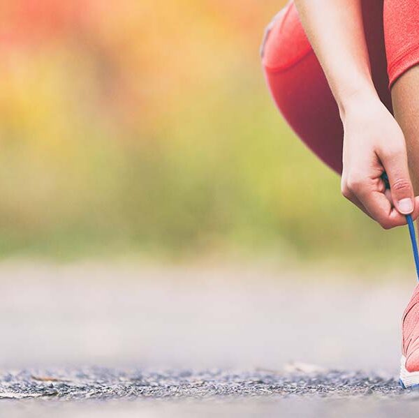 jogger in crop trousers kneeling down tying their laces